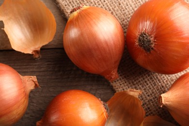 Many ripe onions on wooden table, flat lay