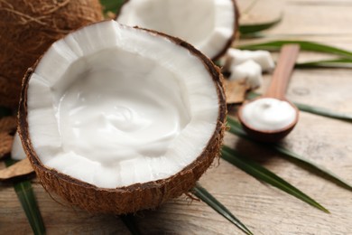 Photo of Ripe coconut with cream on wooden table. Space for text