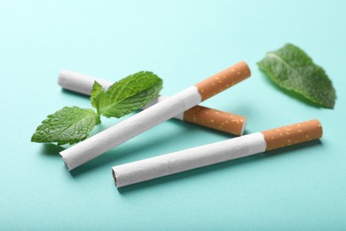 Photo of Menthol cigarettes and mint on turquoise background