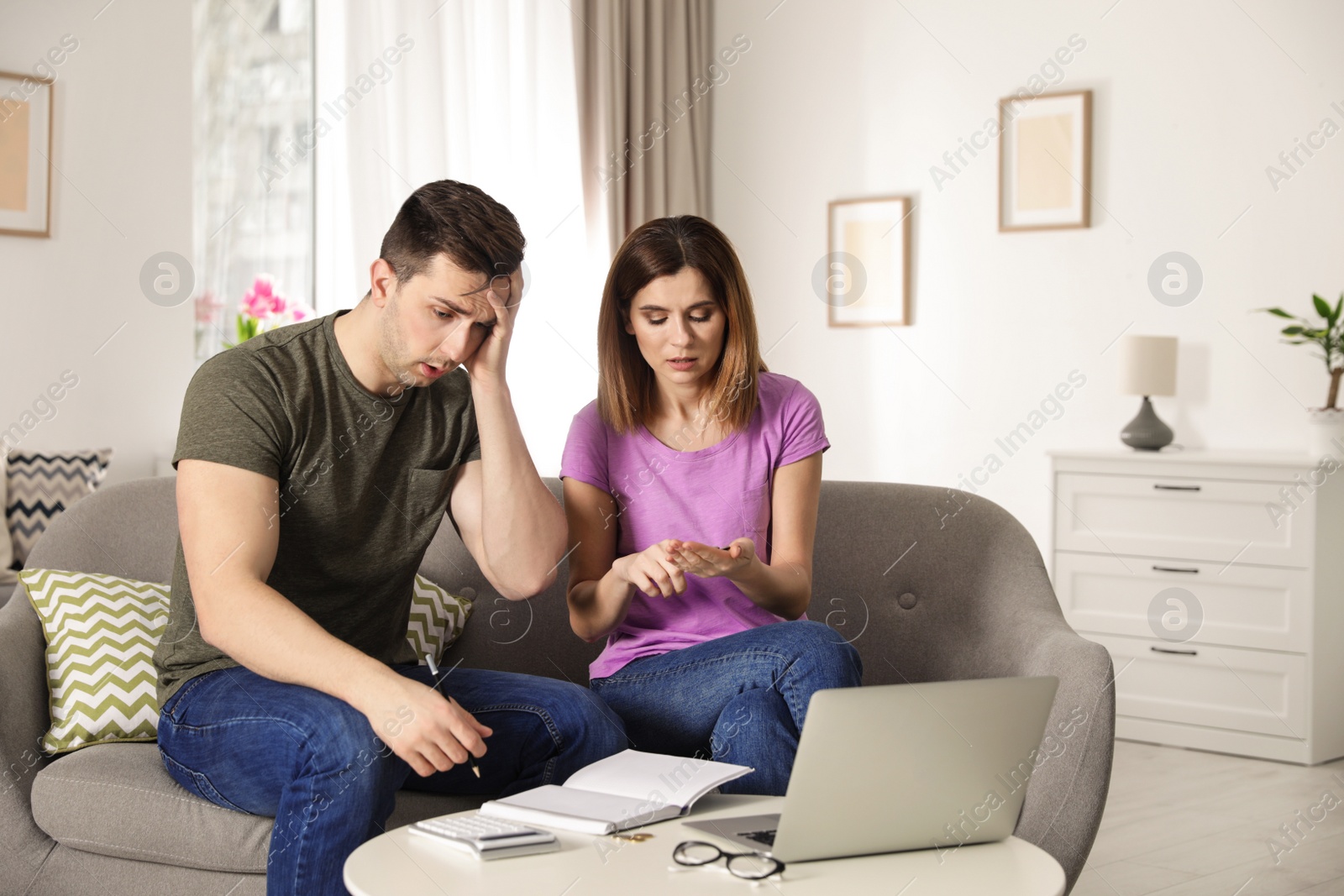 Photo of Sad couple counting money in living room