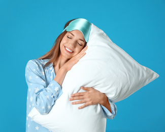 Beautiful woman with pillow on light blue background. Bedtime