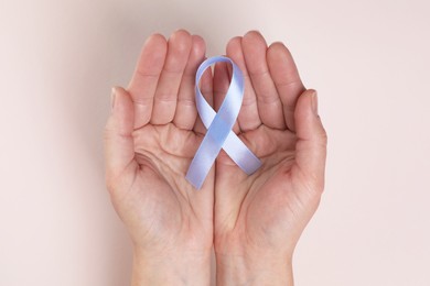 International Psoriasis Day. Woman with light blue ribbon as symbol of support on beige background, top view