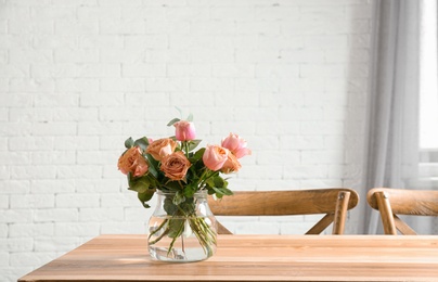 Vase with beautiful flowers as element of interior design on table in room. Space for text