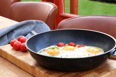 Delicious fried eggs with tomatoes and pepper served on wooden table
