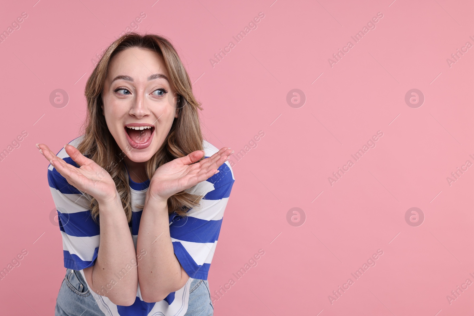 Photo of Portrait of happy surprised woman on pink background. Space for text