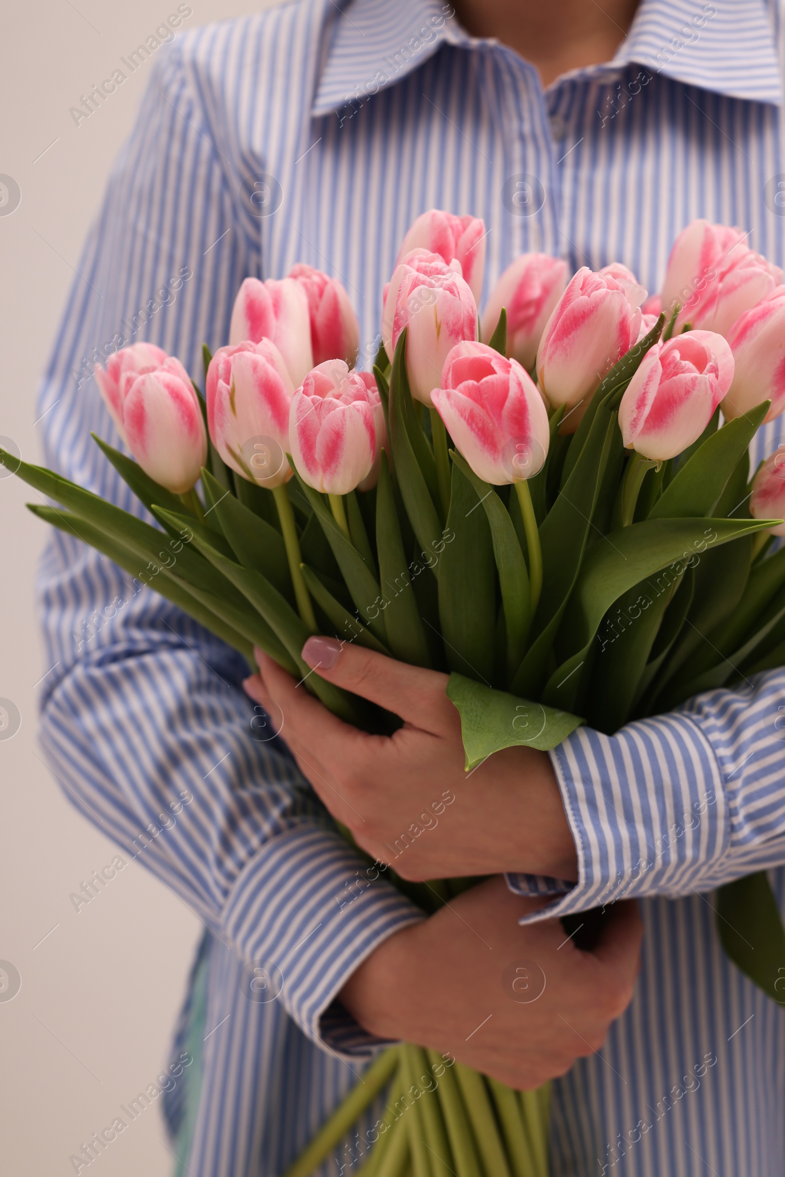 Photo of Woman with bouquet of beautiful fresh tulips on light grey background, closeup