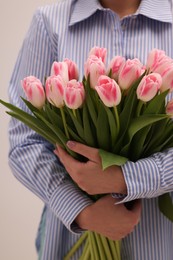 Woman with bouquet of beautiful fresh tulips on light grey background, closeup