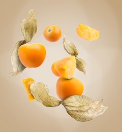 Image of Ripe orange physalis fruits with calyx falling on beige gradient background