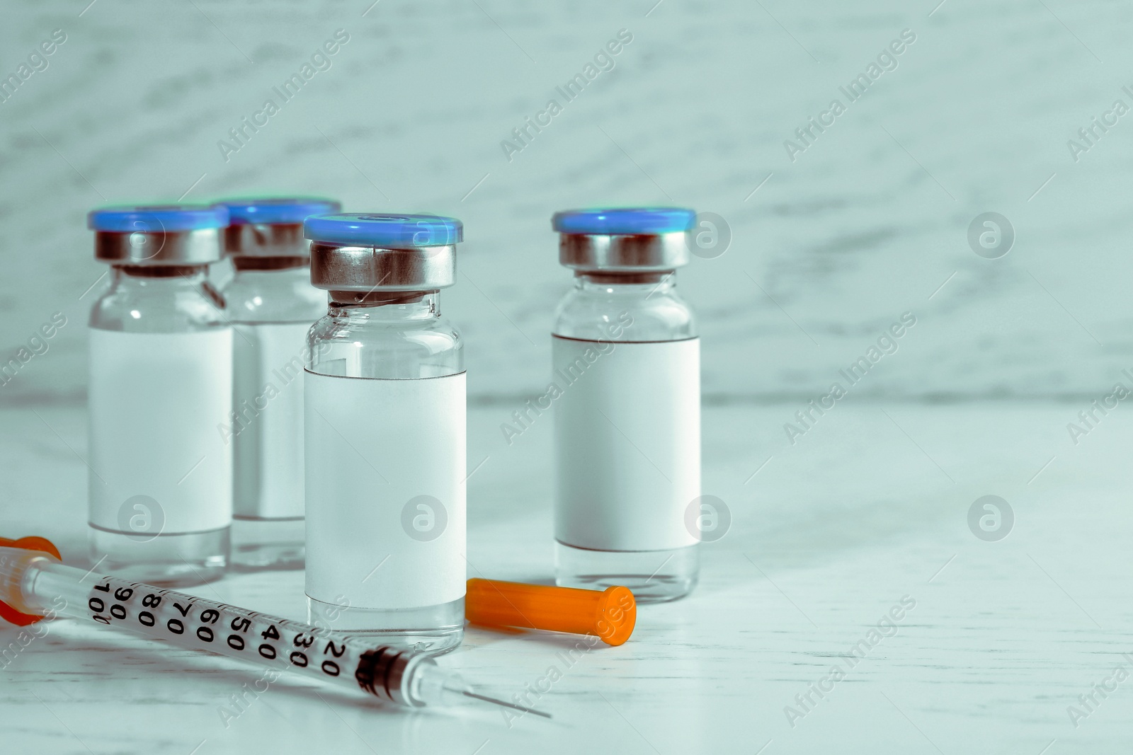 Image of Medication in glass vials and syringe on white wooden table, space for text