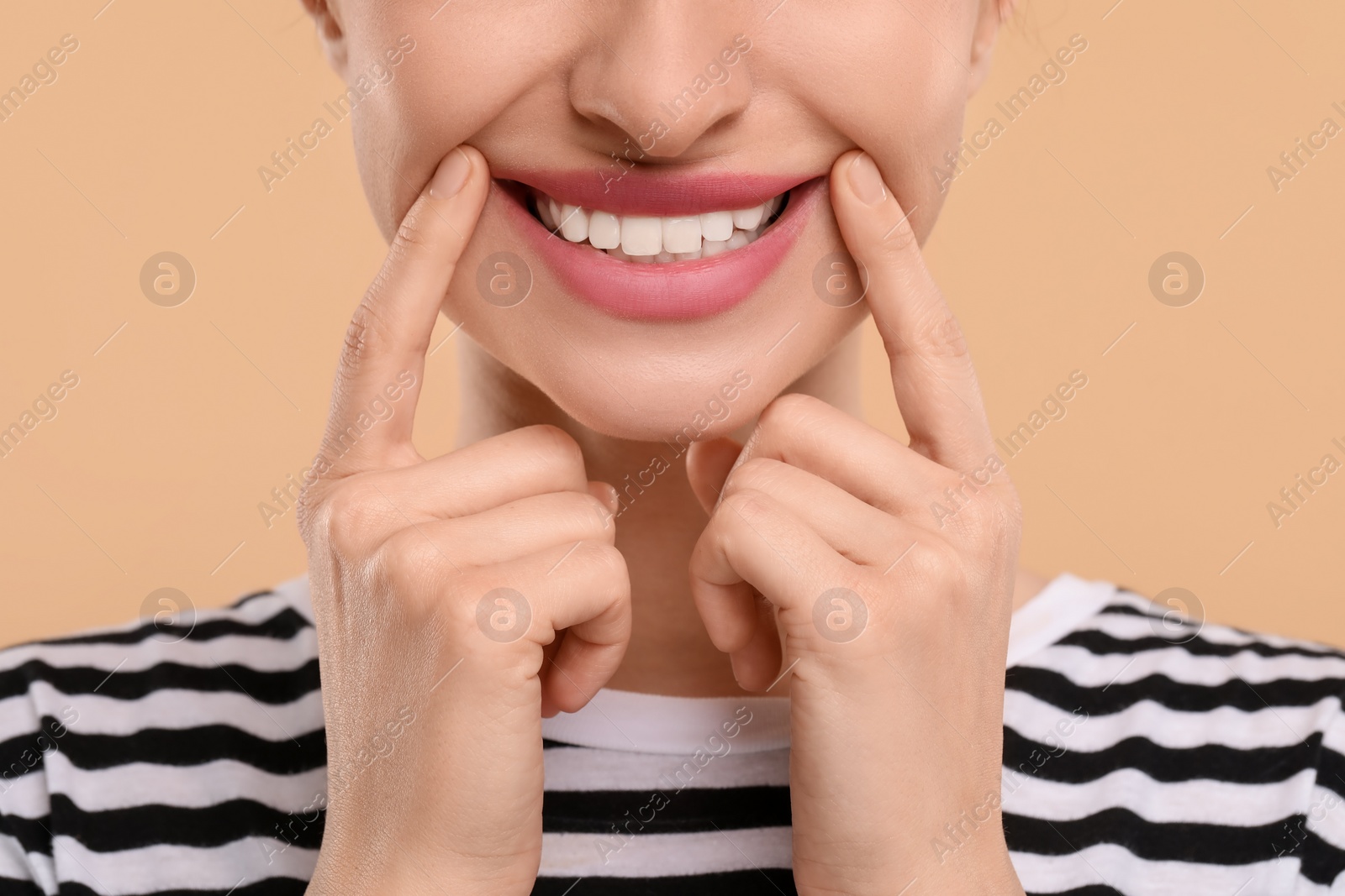 Photo of Woman showing her clean teeth and smiling on beige background, closeup