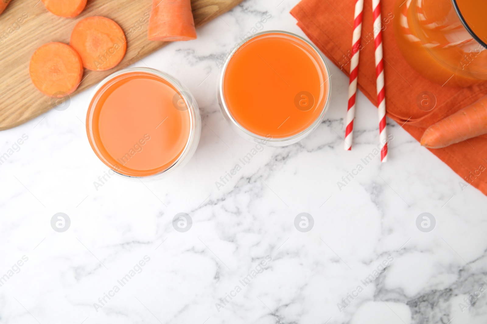 Photo of Freshly made carrot juice on white marble table, flat lay. Space for text