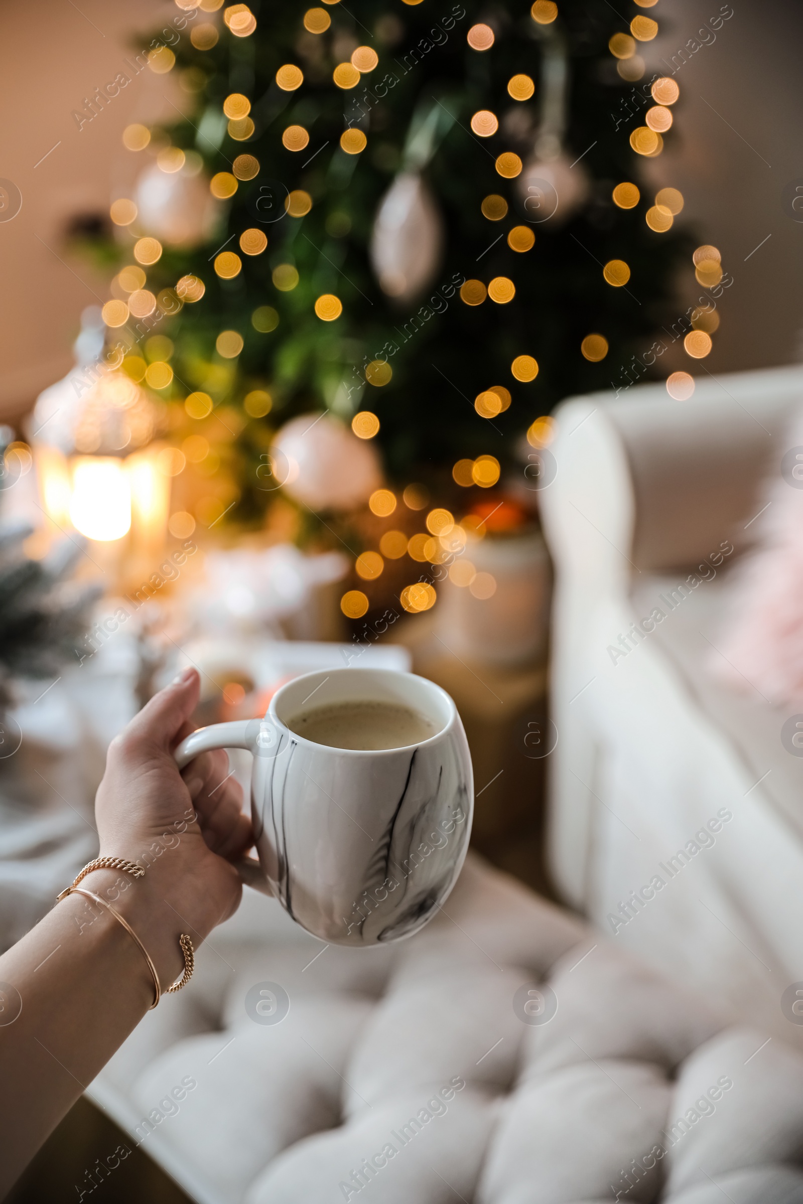 Photo of Woman with cup of cocoa in room decorated for Christmas, closeup