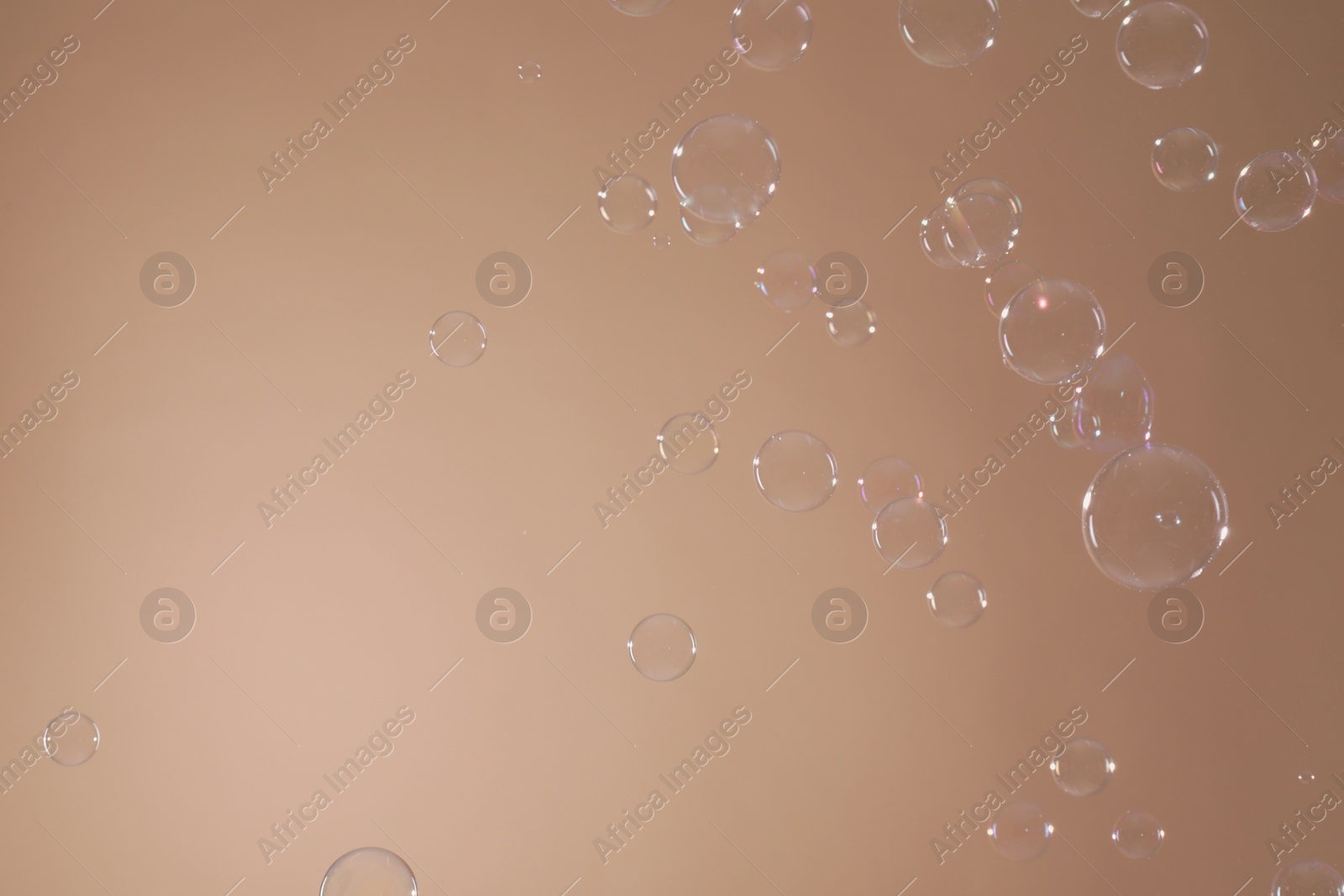 Photo of Many beautiful soap bubbles on light brown background