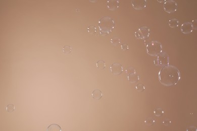 Many beautiful soap bubbles on light brown background