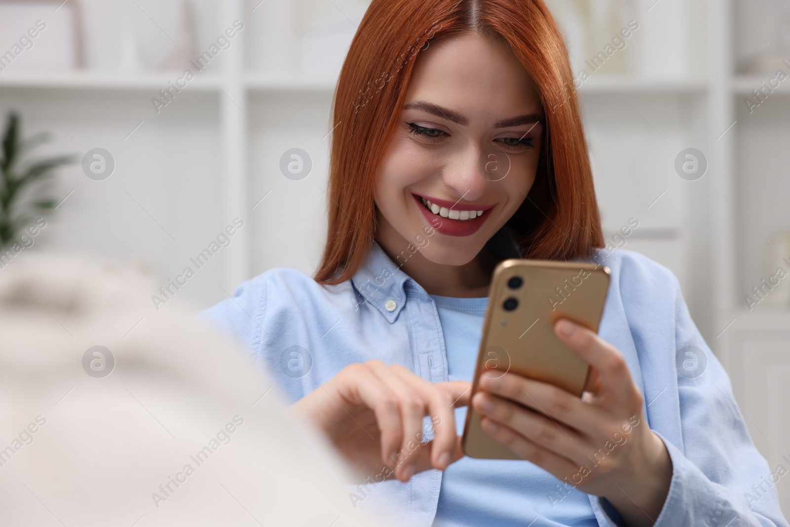 Photo of Happy woman sending message via smartphone on couch at home