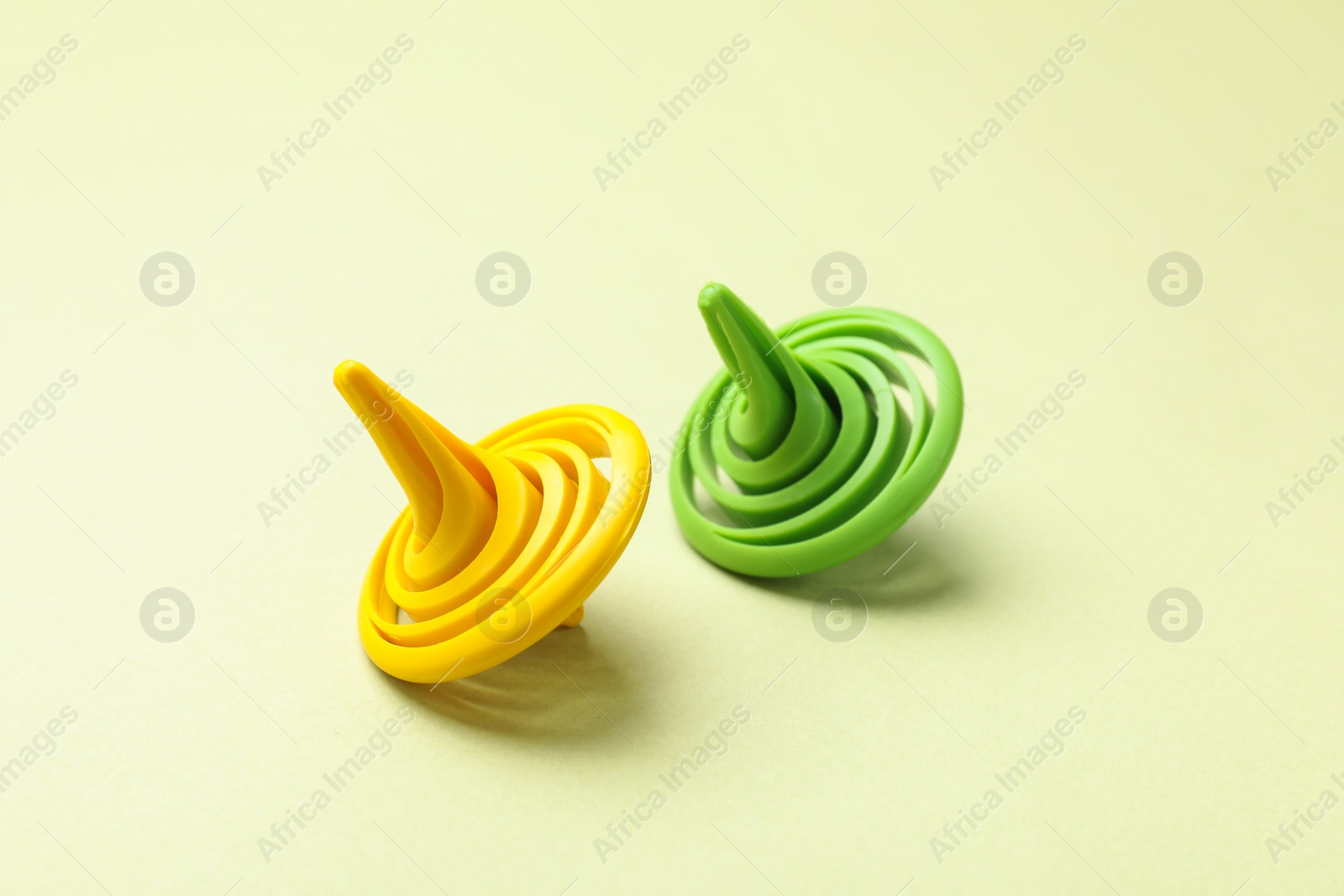 Photo of Two colorful spinning tops on green background, closeup