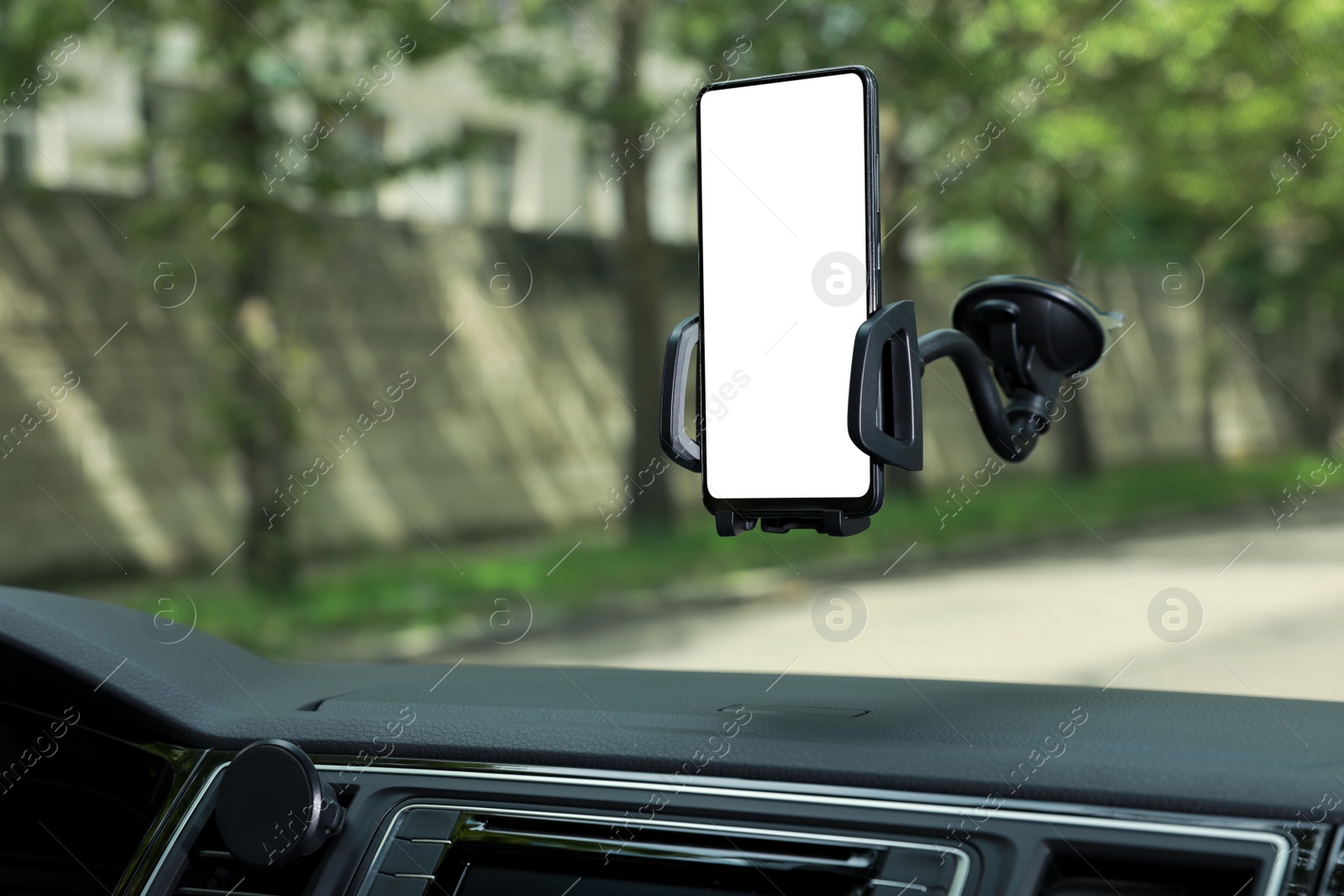 Photo of Car holder with modern mobile phone on windshield of automobile. Mockup for design