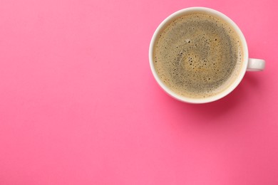 Photo of Fresh coffee in cup on pink background, top view. Space for text