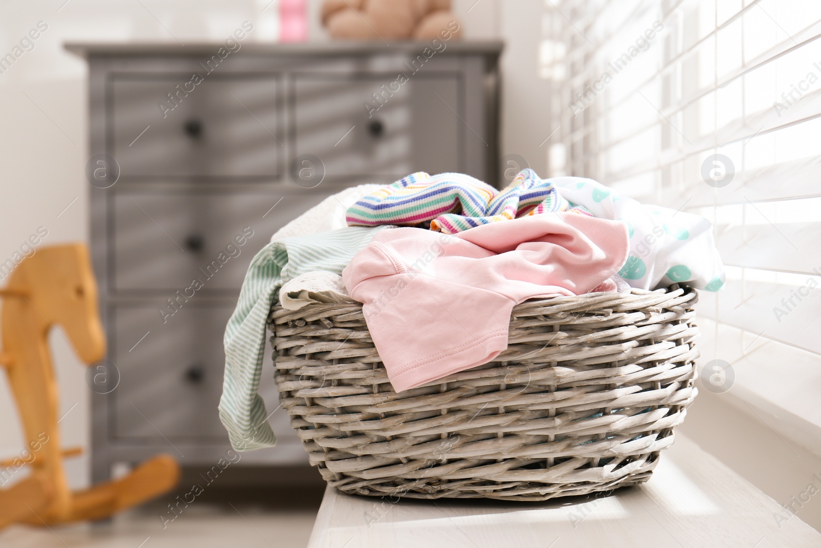 Photo of Wicker laundry basket with different clothes on window sill indoors
