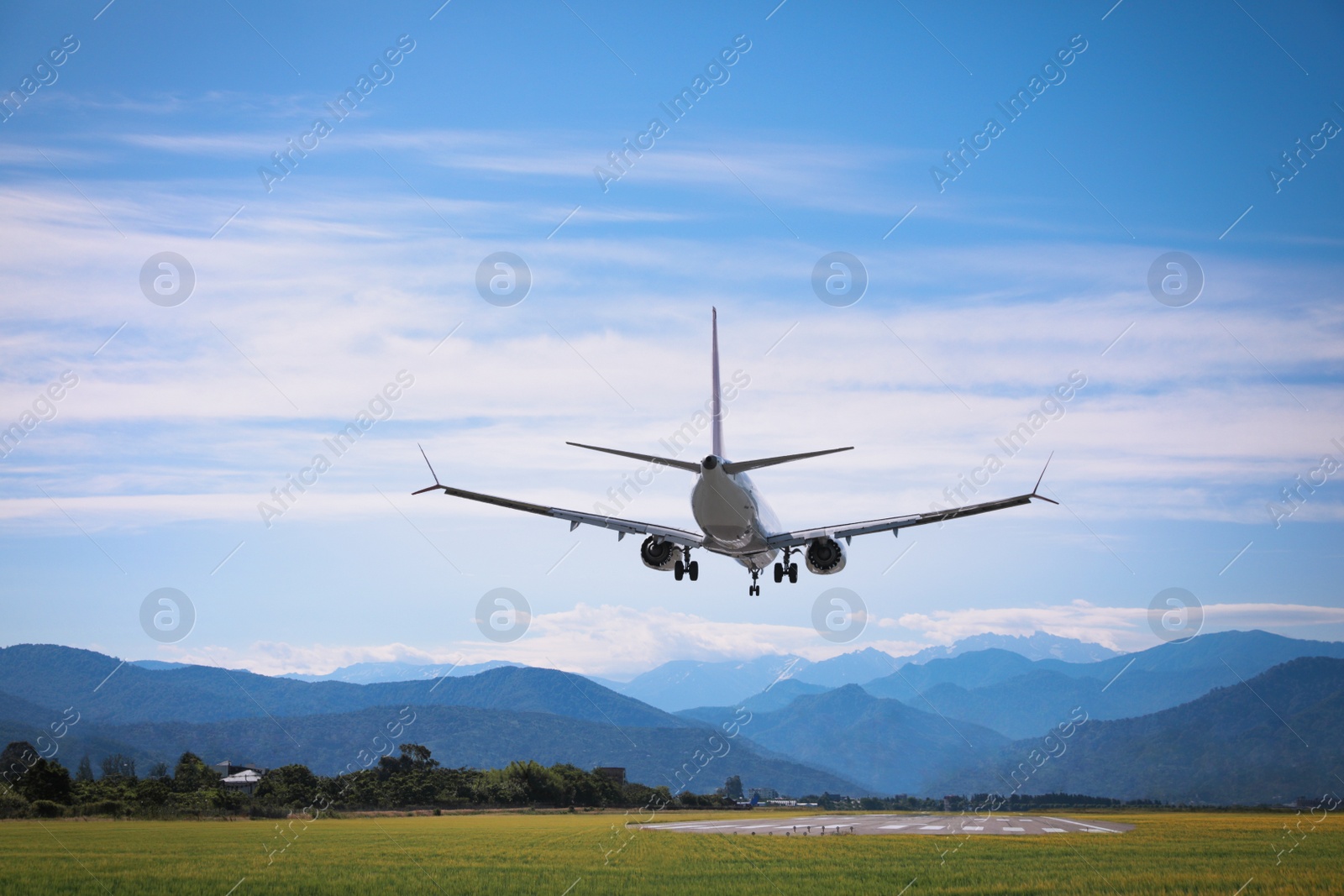 Photo of Modern white airplane landing on runway near mountains