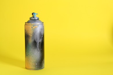 One spray paint can on yellow background, space for text