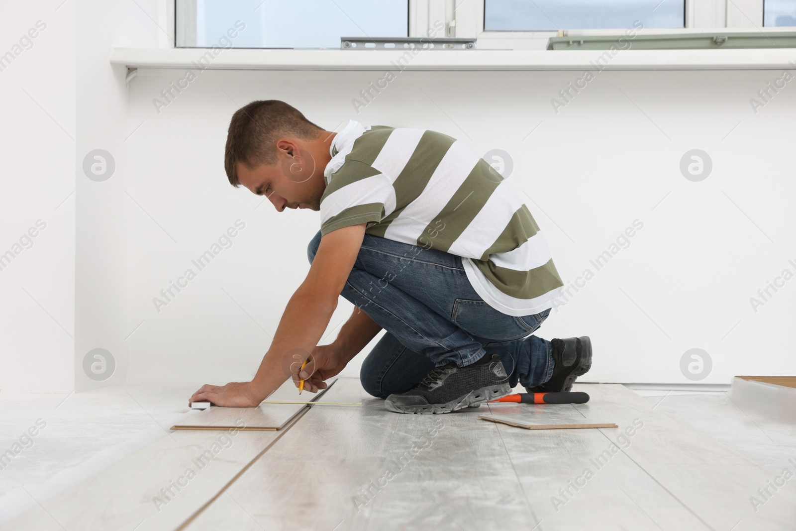 Photo of Professional worker installing new laminate flooring indoors