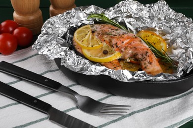 Photo of Tasty salmon baked in foil with citrus fruits and rosemary served on table, closeup