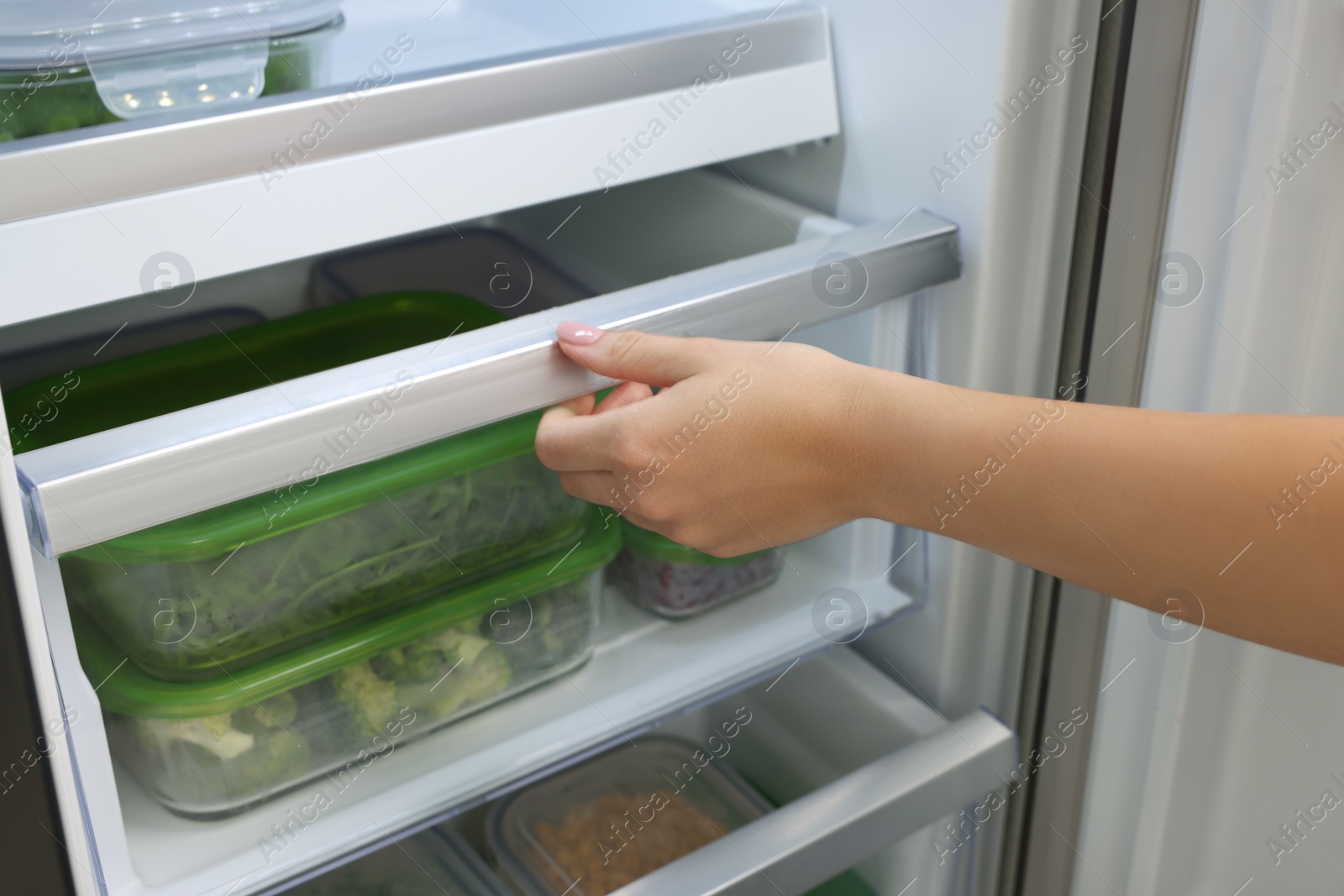 Photo of Woman pulling out fridge drawer with different fresh products, closeup. Food storage