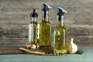 Photo of Cooking oil with different spices and herbs in bottles on wooden table
