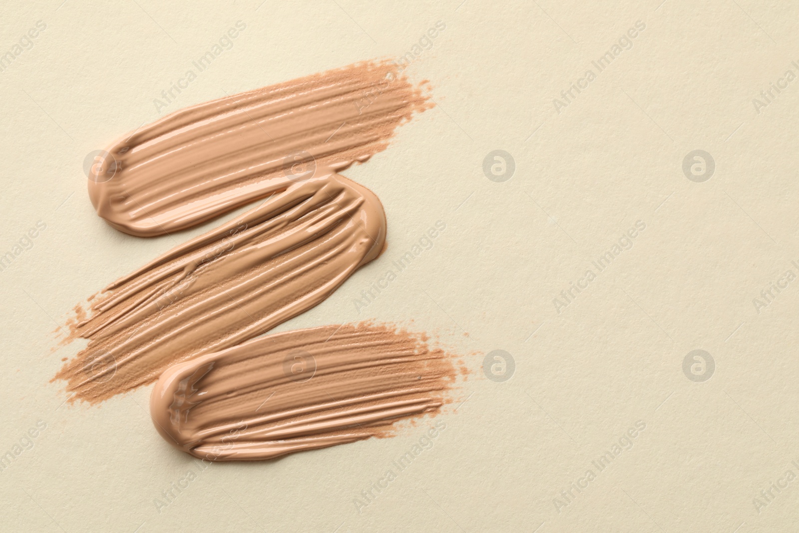 Photo of Samples of liquid skin foundations on beige background, top view. Space for text