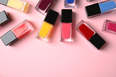 Bottles of nail polish on color background, top view with space for text