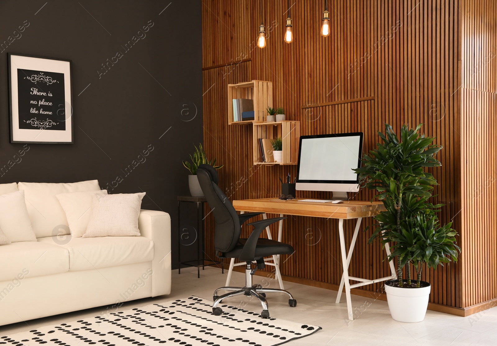 Photo of Comfortable workplace with computer near wooden wall in stylish room interior. Home office design