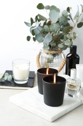 Burning aromatic candles and perfume on table, space for text