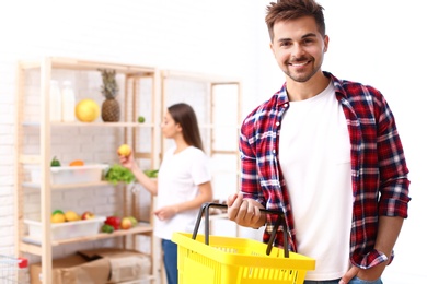 Young man with empty shopping basket in grocery store