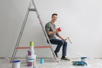 Male decorator sitting on ladder in empty room