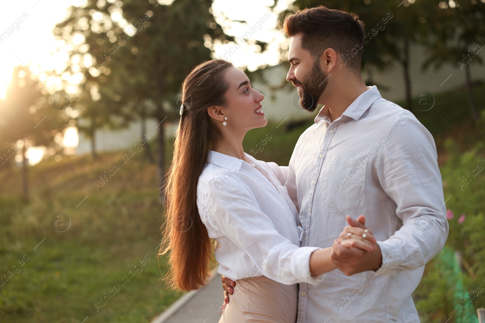 Photo of Lovely couple dancing together outdoors at sunset, space for text