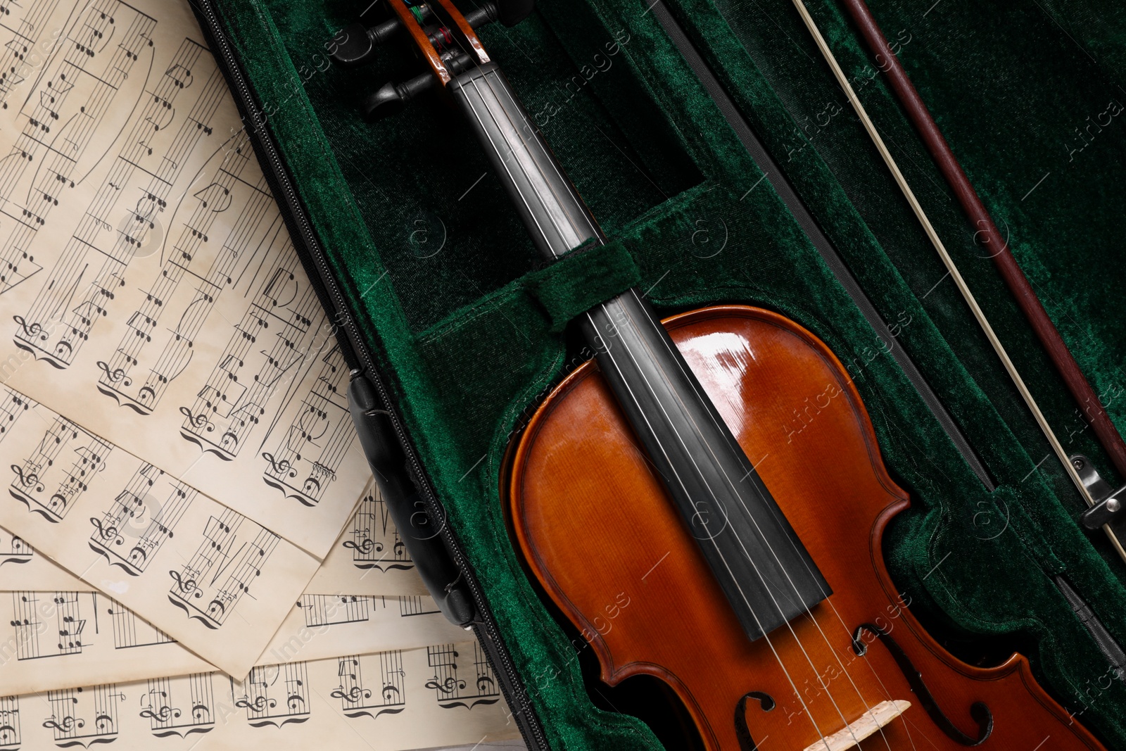 Photo of Violin, bow in case and music sheets on table, top view