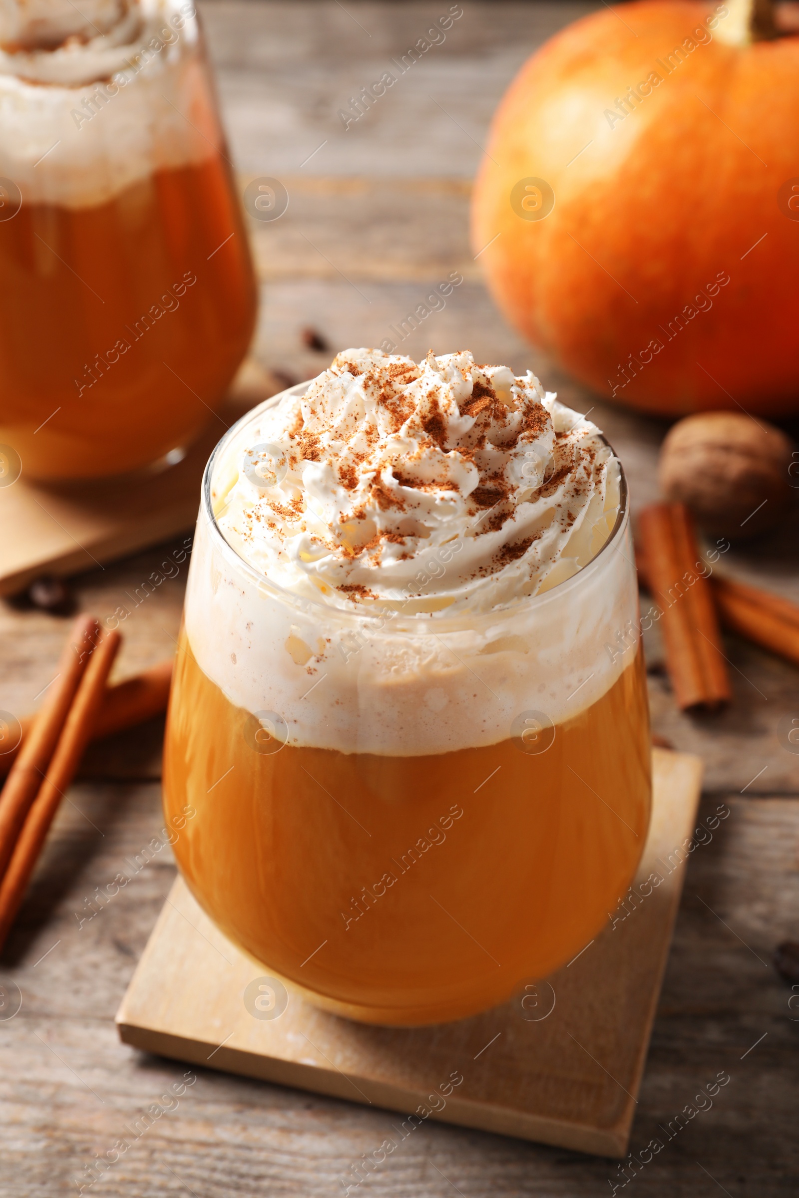 Photo of Glass with tasty pumpkin spice latte on wooden table