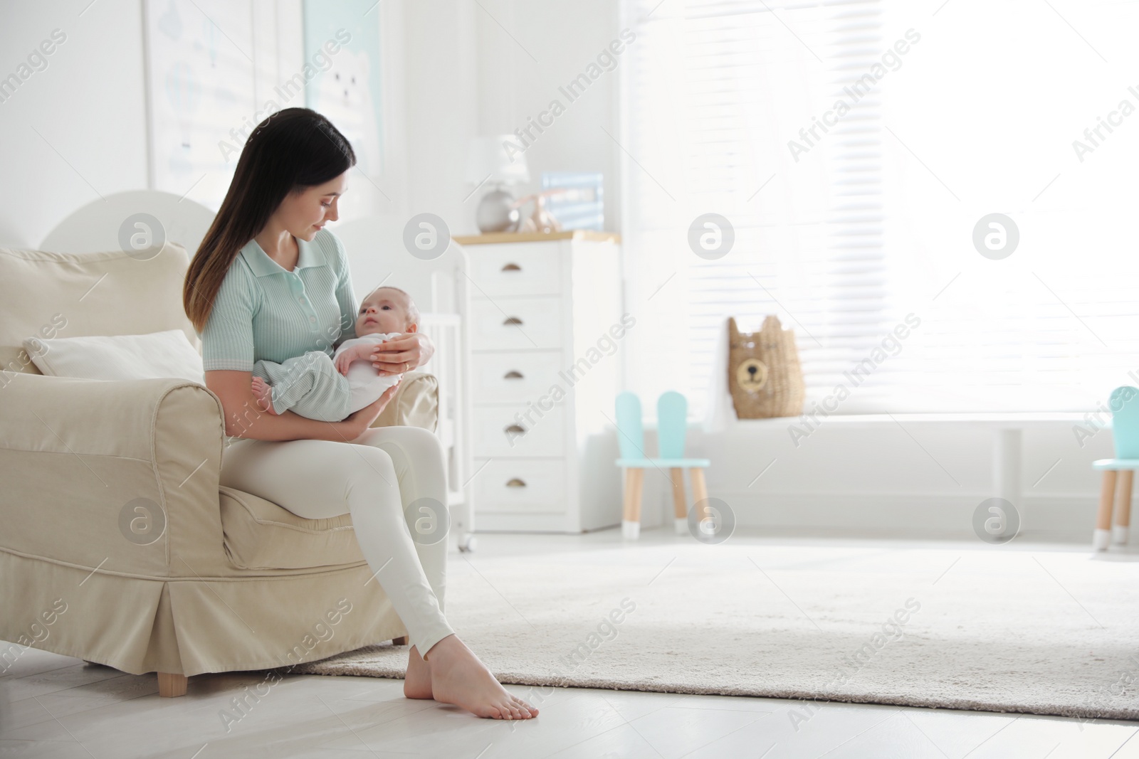 Photo of Young woman with her cute baby at home, space for text