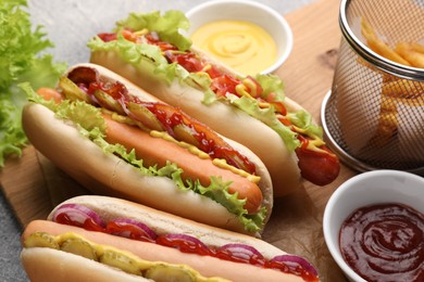 Delicious hot dogs with different toppings served on table, closeup