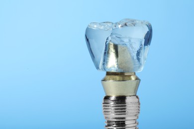 Educational model of dental implant on light blue background, closeup. Space for text