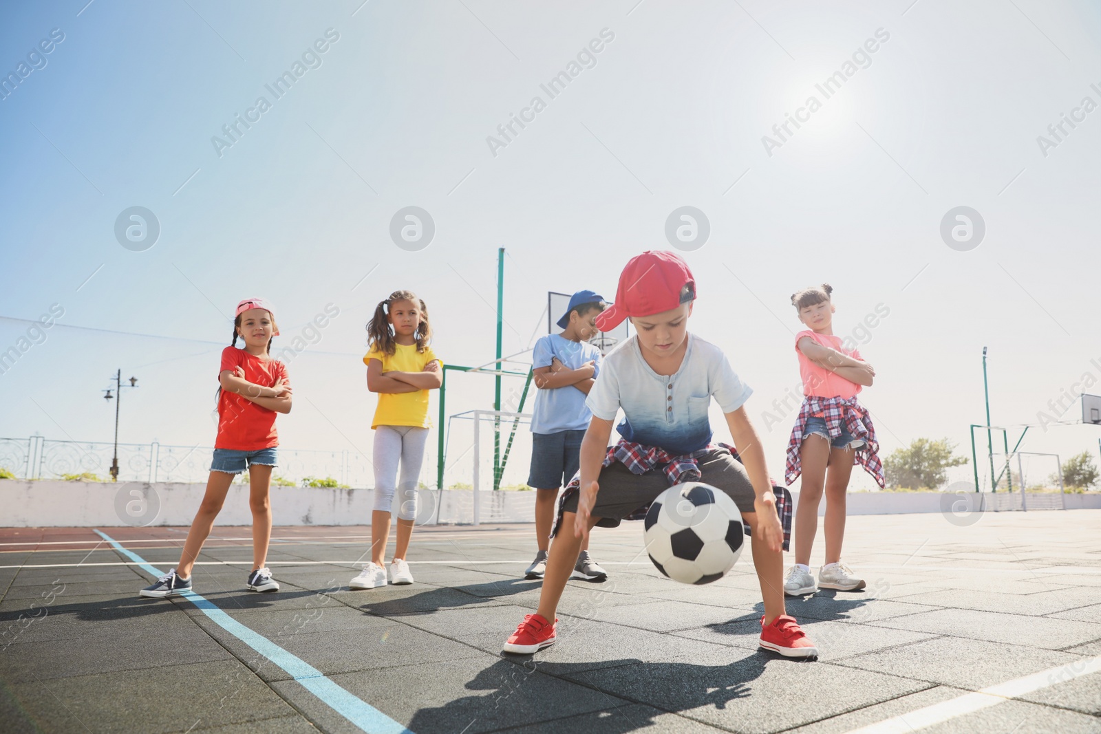 Photo of Cute children with soccer ball at sports court on sunny day. Summer camp