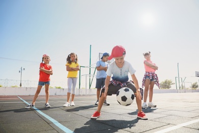 Photo of Cute children with soccer ball at sports court on sunny day. Summer camp