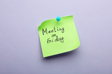Photo of Paper note with words Meeting on Friday pinned to light grey background
