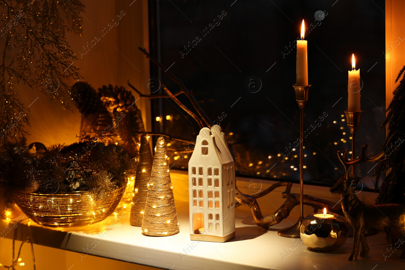 Photo of Many beautiful Christmas decorations, candlesticks and festive lights on window sill indoors
