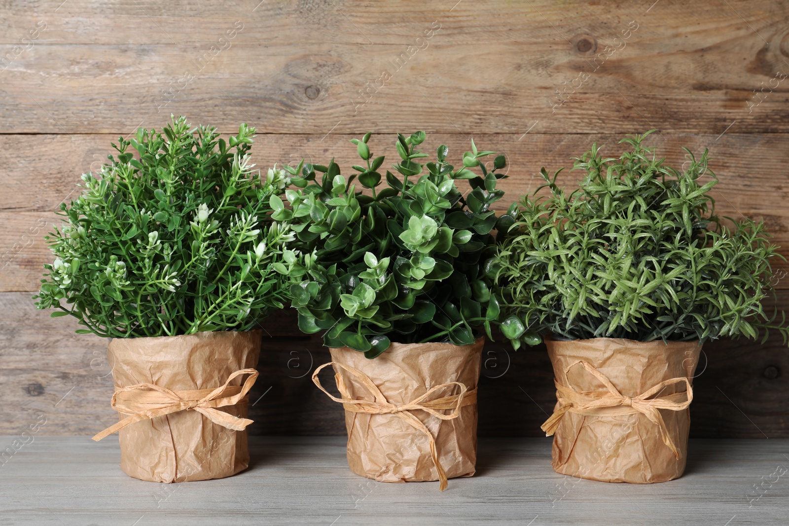 Photo of Different artificial potted herbs on white wooden table