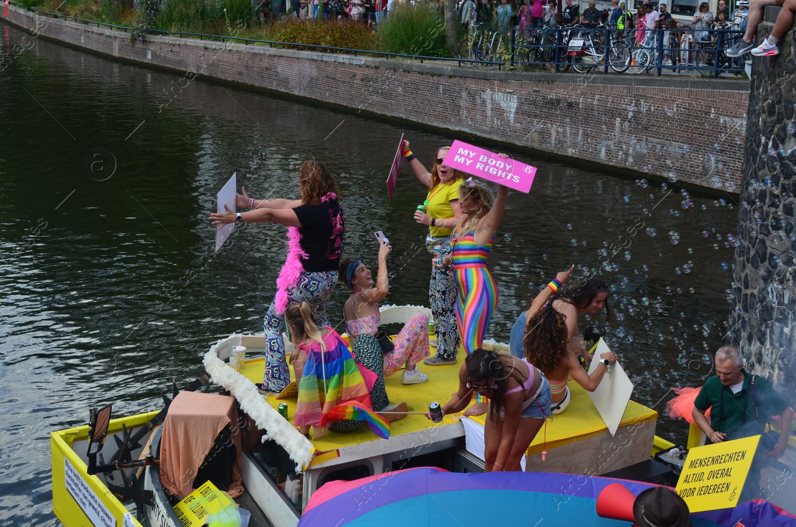 Photo of AMSTERDAM, NETHERLANDS - AUGUST 06, 2022: Many people in boat at LGBT pride parade on river