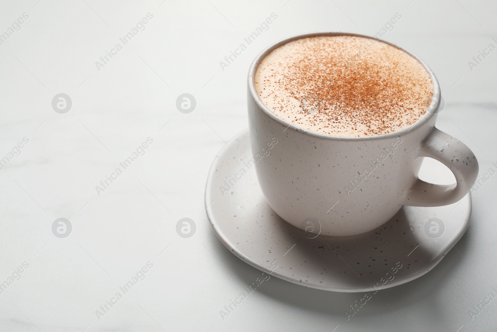 Photo of Delicious eggnog with cinnamon on white marble table, closeup. Space for text