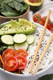 Photo of Delicious poke bowl with vegetables, avocado and mesclun on white table