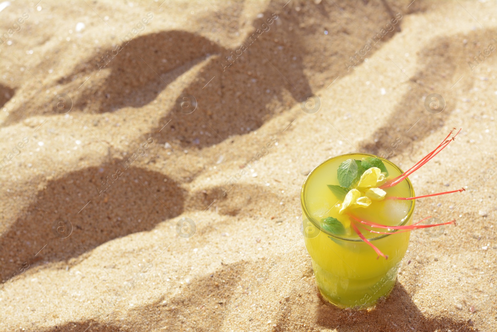 Glass of refreshing drink on sand. Space for text Photo of Glass of refreshing drink on sand. Space for text